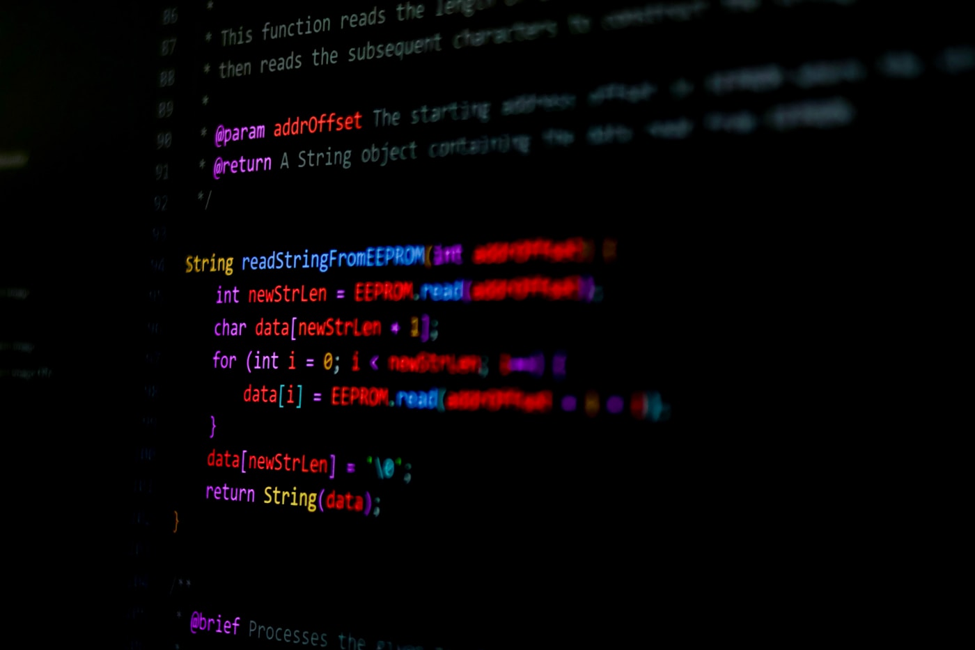 Close-up of lines of code on a dark screen with warm red and yellow syntax